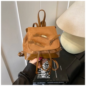 Detail of a brown leather mini backpack with cute bows and premium mixed textures