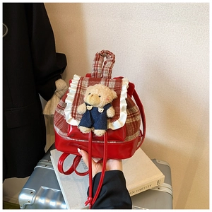 Detail of red plaid backpack with cute teddy bear plush and white lace trimming