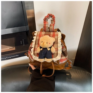 Close-up of vintage brown leather kids backpack with lace trim and plush bear doll