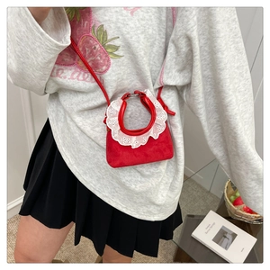 Vue détaillée d'un mini sac rouge pour enfants avec dentelle blanche et bandoulière