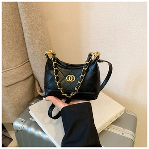Detail of black quilted mini bag with gold chain strap and interlocking metal logo
