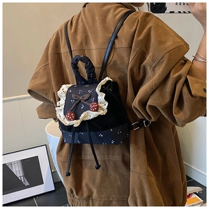 Détail d'un sac à dos mignon avec bordure en dentelle blanche et breloques de cerise