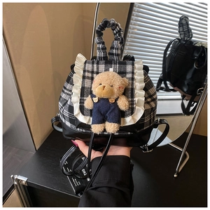 Detail of checkered backpack with white lace edges and a cute plush bear charm