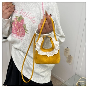 Makroaufnahme der gelben Mini-Handtasche mit weißer Spitze und Wildleder-Textur
