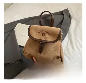 Close-up of brown suede mini backpack with flower embroidery and leather buckle detail