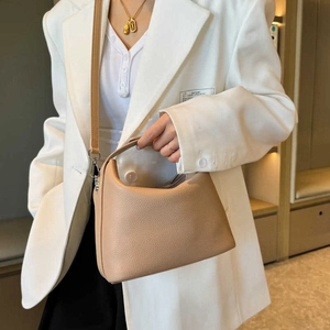 Schicke beige Handtasche aus Leder mit Lychee-Maserung, von Model zu Anzug getragen