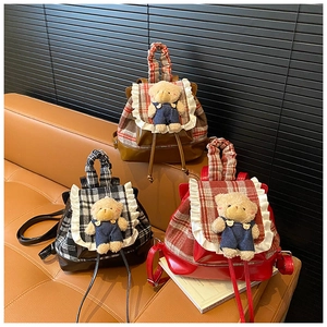 Close-up of three plaid school backpacks with teddy bear charms and lace trim edges