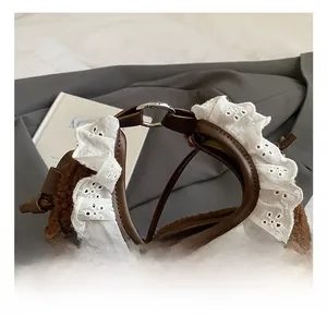 Detail of plush handbag handle with brown leather trim and white lace ruffles