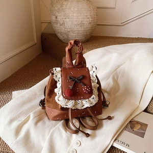 Détail du mini sac à dos marron floral avec dentelle blanche et noeud cerise décoré