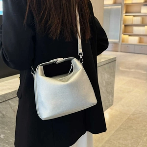 Schicke silberne Handtasche aus genarbtem Leder mit Umhängeriemen auf schwarzem Blazer