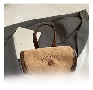Detail of flower embroidery and logo on brown frosted suede vintage bucket backpack
