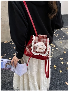 Detalle de mochila roja a cuadros para niños con perrito de peluche y encaje blanco