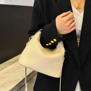 Beigefarbene Handtasche aus Leder mit silberner Hardware an einem schicken Modell