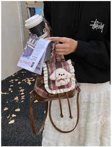 Detalle de mochila de cuadros marrones con peluche de perrito 3D y ribete de encaje