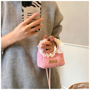 Detail of pink faux shearling mini handbag featuring white lace trim and handmade leather tag