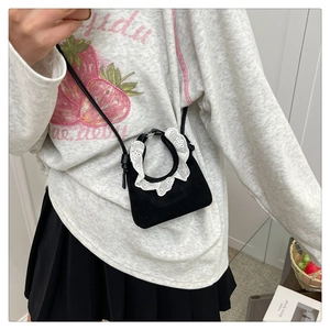 Detailaufnahme einer kleinen schwarzen Wildledertasche mit eleganten weißen Spitzenrüschen