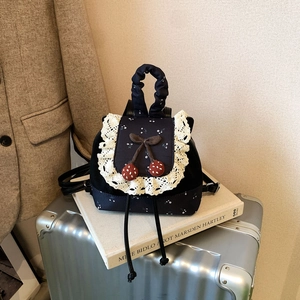 Détail du sac à dos scolaire avec bordures en dentelle, cerises et motifs floraux