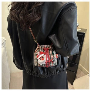 Detail of mini Christmas plaid bucket bag with Santa patch and chain strap worn by a child