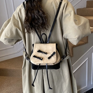 Chic beige and black bow backpack with contrast stitching on a stylish model