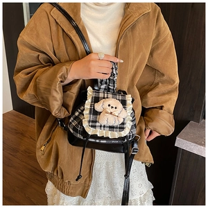 Detalle de una mini mochila de cuadros con encaje y colgante de perro de peluche en modelo