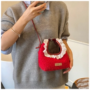 Close-up of a red plush crossbody bag with lace trim and handmade vintage label