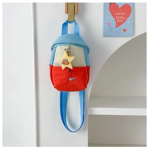 Detail of color-block kids mini bag featuring a yellow star pendant and long strap