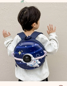 Rear view of child wearing dark blue space-themed hardshell backpack with astronaut print