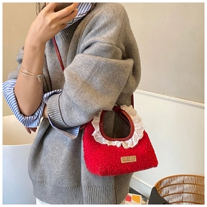 Detail of red sherpa mini crossbody bag with white lace trim and handmade leather label