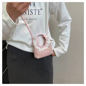 Mini sac bandoulière rose avec bordure en dentelle blanche porté par un mannequin
