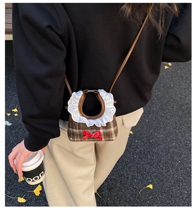 Detail of a brown plaid mini bag for girls with lace collar and red sequin bow