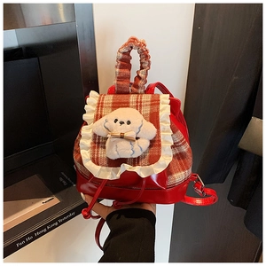 Detalle de mochila roja para niños con cuadros, peluche de perrito y asa con volantes