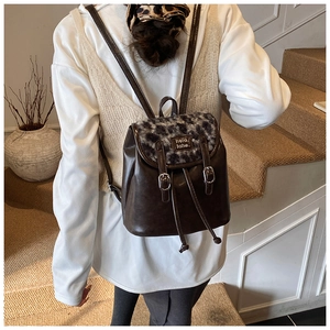 Detailopname van een mini-rugzak met luipaardprint gedragen door een model binnen