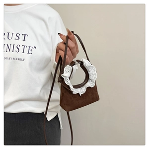 Détail d'un mini sac à main marron avec d'élégantes finitions en dentelle sur la poignée