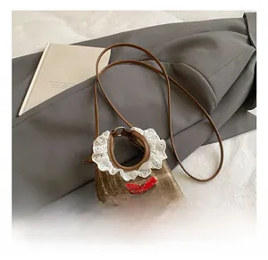 Detail of brown plaid wool mini bag featuring lace trim and a red shiny ribbon bow