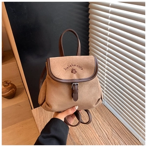 Close-up of brown suede mini backpack featuring vintage embroidery and metallic buckle