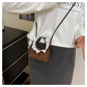 Détail d'un mini sac à main en daim marron avec dentelle blanche et bandoulière