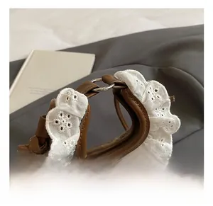 Detailed close-up of brown plush handbag featuring delicate white lace trim and leather handle