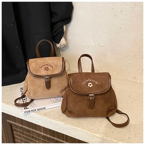 Detail of vintage suede mini backpacks featuring elegant flower embroidery and buckle straps