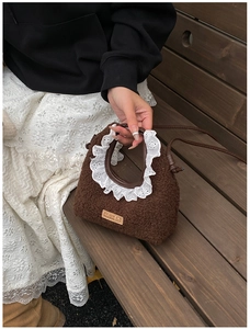 Detail of brown faux shearling handbag featuring white lace trim and leather hand-made tag
