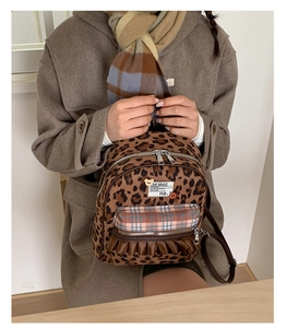 Detail shot of a vintage leopard print backpack with cute lace ruffles and plaid pocket.