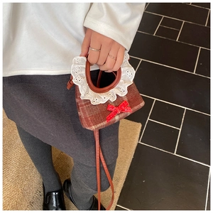 Detail of red plaid girls' handbag with decorative bow and delicate white lace handle