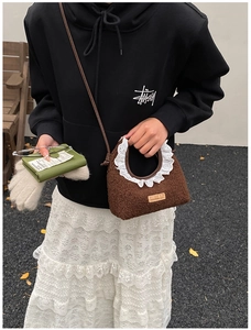 Detailed close-up of brown plush handbag with white lace trim and leather strap