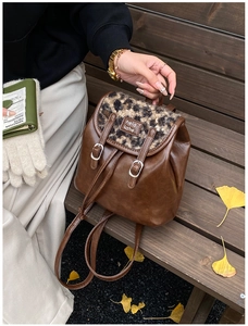 Dettaglio zaino vintage in pelle marrone con patta leopardata e foglie autunnali