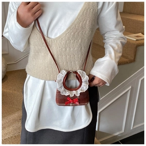 Detail of red plaid mini handbag featuring white lace collar and red sequined bow accessory