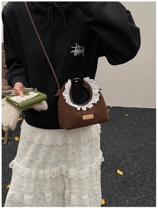 Detail of a brown fuzzy plush bag with white lace trim and handmade leather patch