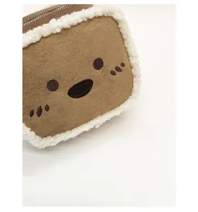 Detail of cute cat face embroidery on brown suede handbag with white fleece trim