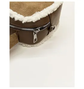 Detailed close-up of brown suede heart bag with white plush trim and silver metal zipper