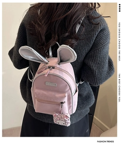 Pink mini backpack for kids featuring silver bunny ears and leopard cat plush charm detail