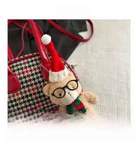 Détail d'un ours en peluche avec bonnet de Noël et écharpe sur un petit sac à carreaux