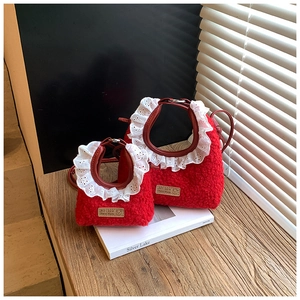 Detail of red plush kids handbag with white lace trim and leather handles on a book